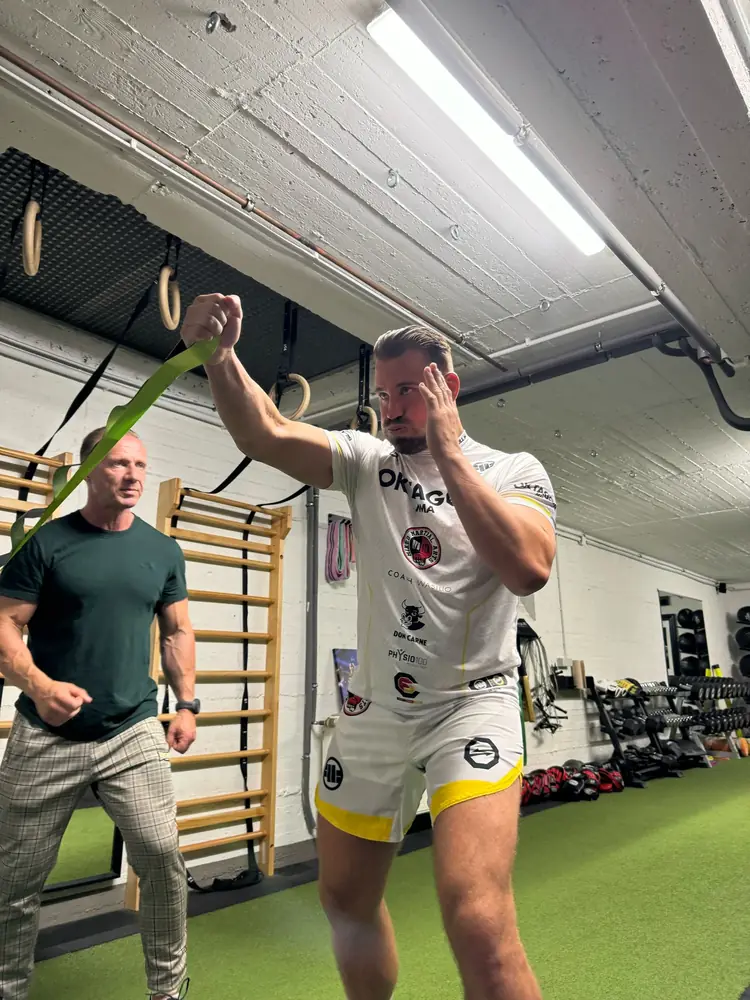 MMA-Kämpfer trainiert Schlagtechnik mit Band, René beobachtet
